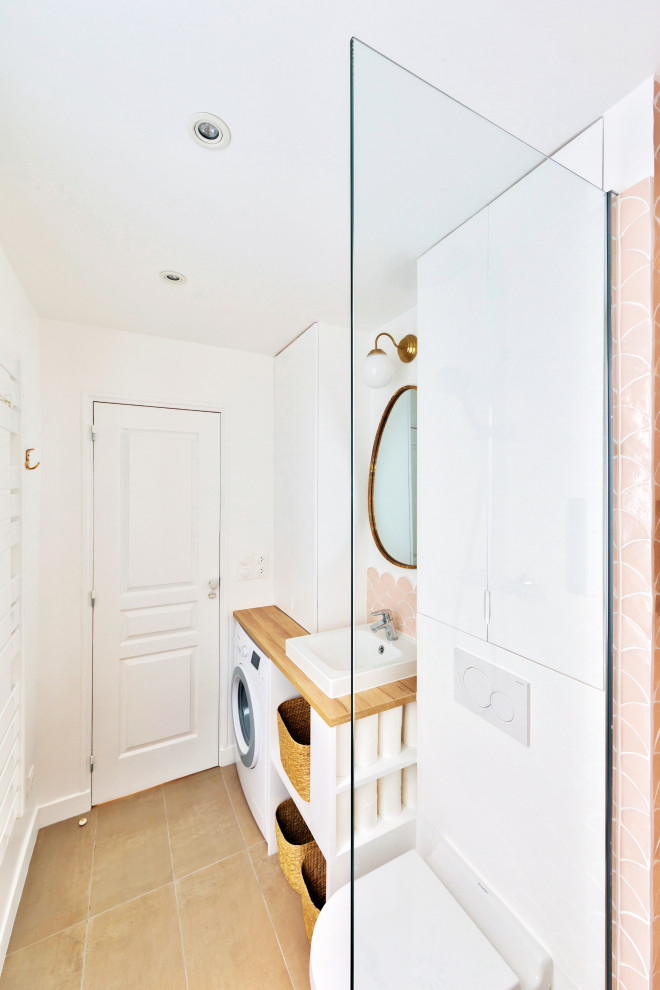 パリにある高級な中くらいなシャビーシック調のおしゃれなバスルーム (浴槽なし) (フラットパネル扉のキャビネット、白いキャビネット、バリアフリー、壁掛け式トイレ、ピンクのタイル、白い壁、コンソール型シンク、木製洗面台、ベージュの床、オープンシャワー、洗面台1つ、造り付け洗面台) の写真