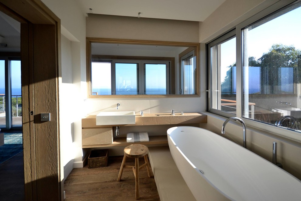 Exemple d'une très grande salle de bain principale tendance avec un plan de toilette en bois, des carreaux de béton, une baignoire indépendante, un mur blanc et une vasque.