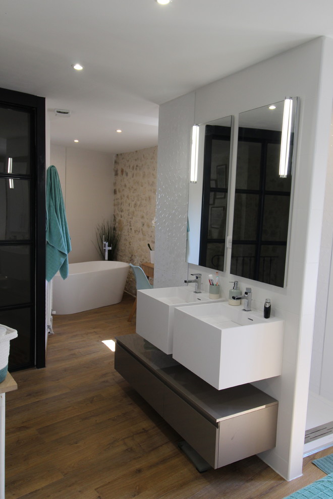 Exemple d'une grande salle de bain principale tendance avec une baignoire posée, une douche double, un carrelage blanc, des carreaux de céramique, un mur blanc, parquet clair, une grande vasque, une cabine de douche à porte battante et un plan de toilette blanc.