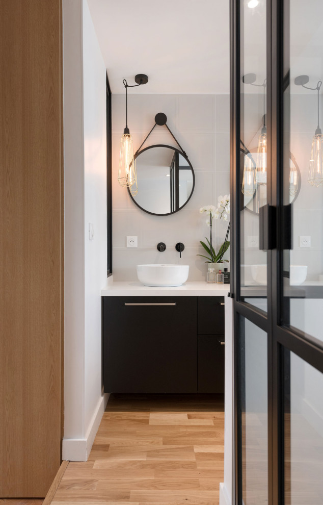 Idéer för mellanstora funkis vitt en-suite badrum, med luckor med profilerade fronter, svarta skåp, vit kakel, keramikplattor, bänkskiva i akrylsten, vita väggar, ljust trägolv och beiget golv