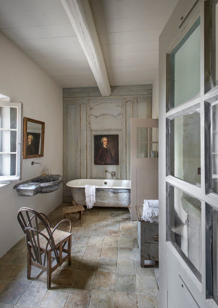 Imagen de cuarto de baño principal campestre grande con lavabo suspendido, bañera con patas, paredes blancas, puertas de armario con efecto envejecido y suelo de baldosas de terracota