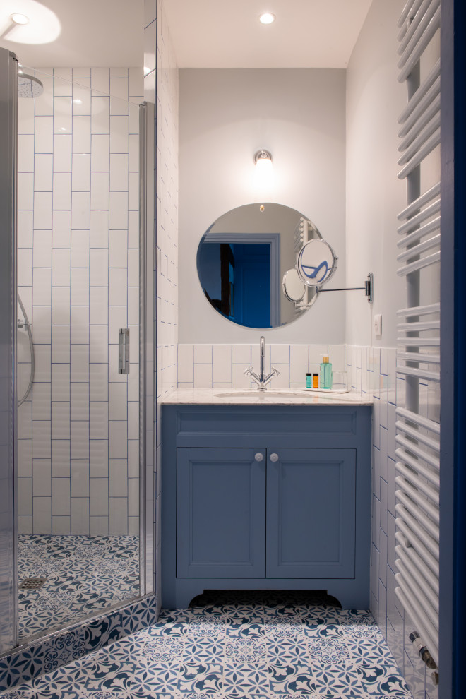 Idée de décoration pour une salle d'eau tradition de taille moyenne avec des portes de placard bleues, une douche d'angle, un carrelage blanc, un mur blanc, un sol en carrelage de terre cuite, un sol bleu, une cabine de douche à porte battante, du carrelage bicolore, meuble simple vasque et meuble-lavabo sur pied.