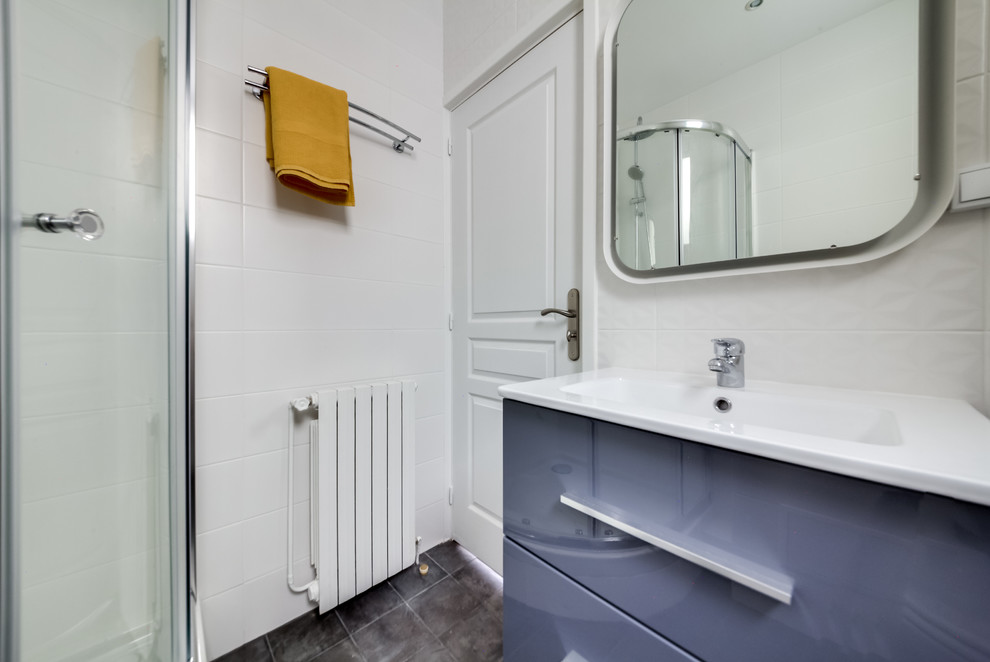 Cette image montre une petite salle de bain principale design avec une douche d'angle, WC suspendus, des carreaux de céramique, un mur blanc, un sol en carrelage de céramique et un carrelage gris.