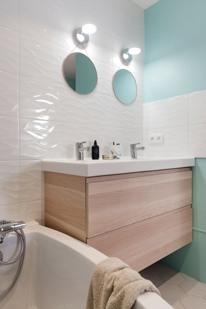 Exemple d'une douche en alcôve principale scandinave en bois clair de taille moyenne avec un placard à porte affleurante, une baignoire d'angle, un carrelage blanc, des carreaux de céramique, un lavabo suspendu, un mur blanc, un sol en carrelage de céramique et un sol beige.