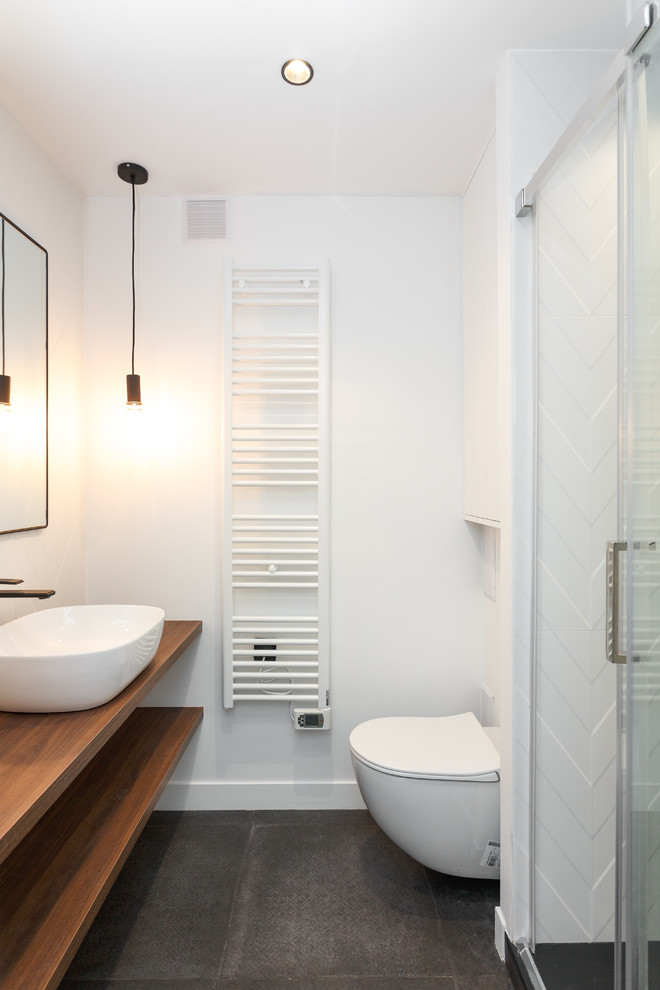 Inspiration for a small modern ensuite bathroom in Other with open cabinets, brown cabinets, a wall mounted toilet, white tiles, ceramic tiles, white walls, ceramic flooring, a vessel sink, wooden worktops, grey floors, a hinged door, brown worktops and an alcove shower.