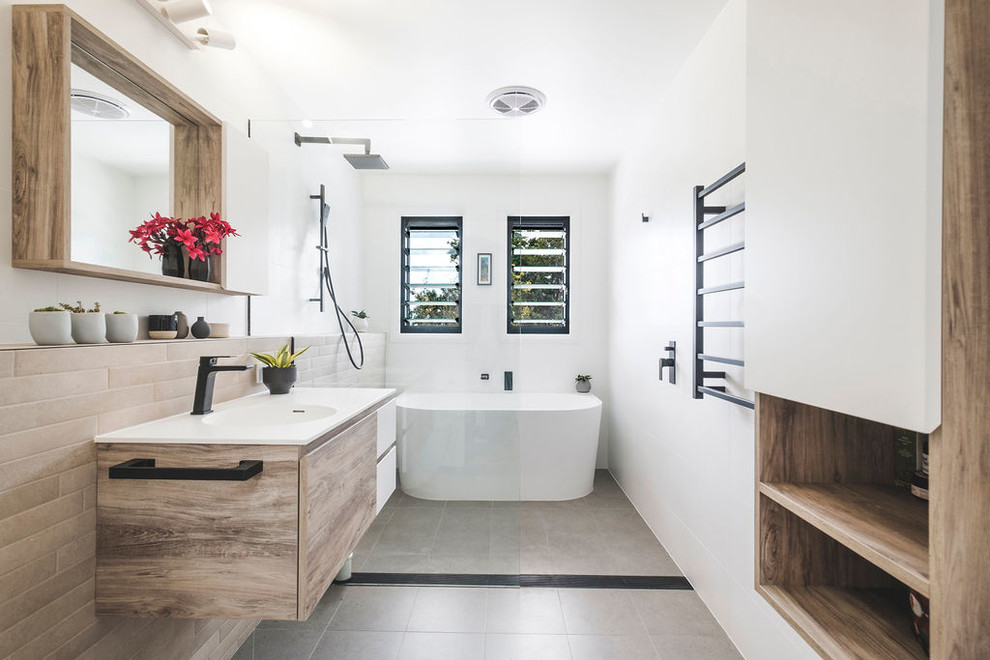 Inspiration för moderna vitt en-suite badrum, med en kantlös dusch, beige kakel, keramikplattor, vita väggar, klinkergolv i keramik, grått golv, släta luckor, skåp i ljust trä, ett fristående badkar, ett väggmonterat handfat och med dusch som är öppen