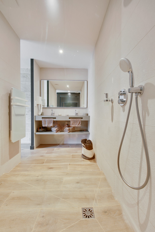 Inspiration for a medium sized contemporary shower room bathroom in Bordeaux with a built-in shower, beige tiles, ceramic tiles, beige walls, wood-effect flooring, a wall-mounted sink, solid surface worktops, brown floors, an open shower, grey worktops and double sinks.