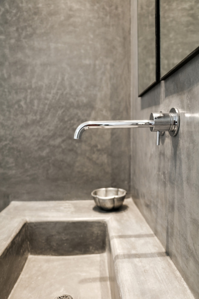 Immagine di una stanza da bagno padronale tropicale con nessun'anta, pavimento in cemento, lavabo a consolle, top in superficie solida, pareti grigie, pavimento grigio, top grigio e un lavabo
