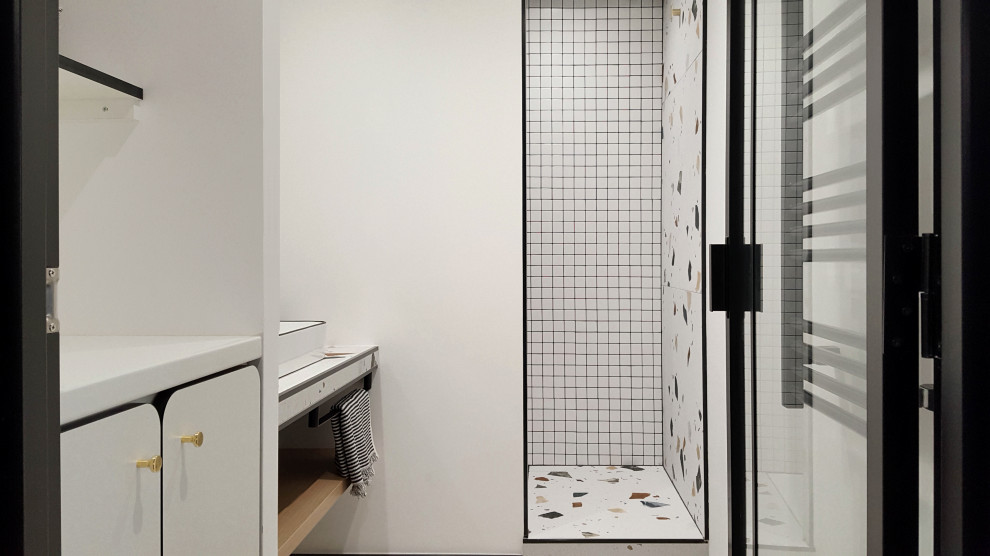 Стильный дизайн: ванная комната среднего размера со стиральной машиной в стиле фьюжн с белыми фасадами, душем в нише, белой плиткой, белыми стенами, полом из керамической плитки, душевой кабиной, раковиной с несколькими смесителями, стеклянной столешницей, разноцветным полом, открытым душем и тумбой под одну раковину - последний тренд
