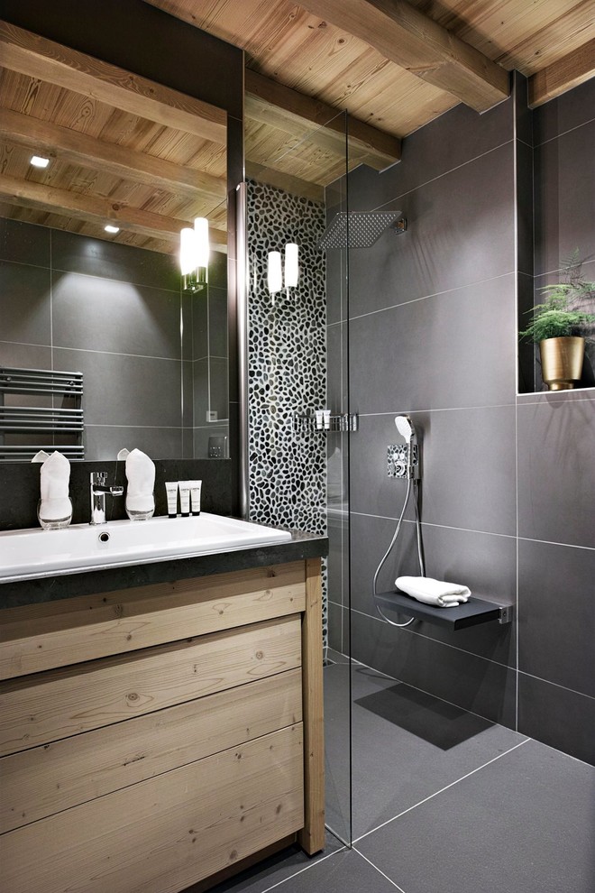 Inredning av ett modernt mellanstort badrum med dusch, med släta luckor, skåp i ljust trä, svart kakel, svarta väggar, ett nedsänkt handfat, en kantlös dusch, keramikplattor och klinkergolv i keramik