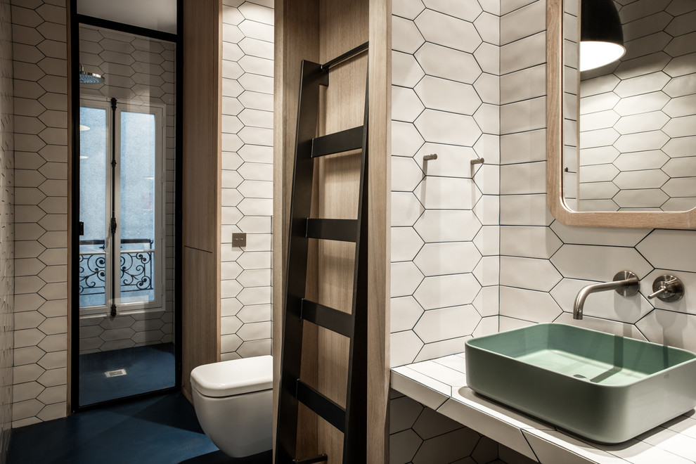 Example of a large trendy 3/4 white tile and ceramic tile concrete floor and blue floor alcove shower design in Paris with a wall-mount toilet, white walls, a trough sink, tile countertops and a hinged shower door