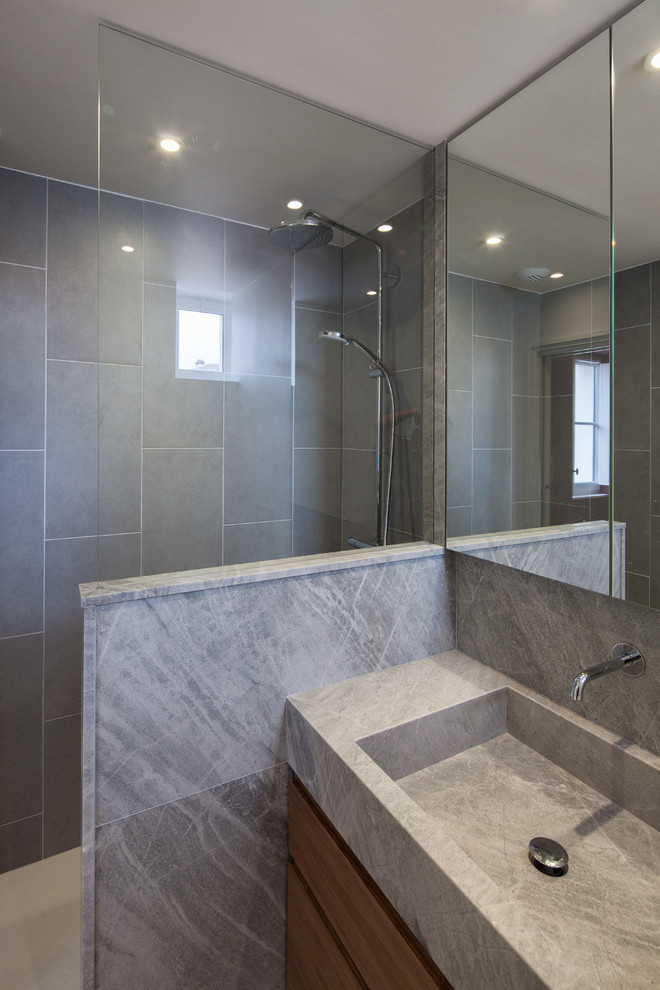 Réalisation d'une petite salle de bain design en bois clair avec un plan vasque, un placard à porte affleurante, un plan de toilette en marbre, un carrelage gris, des carreaux de céramique, un mur beige et un sol en carrelage de céramique.