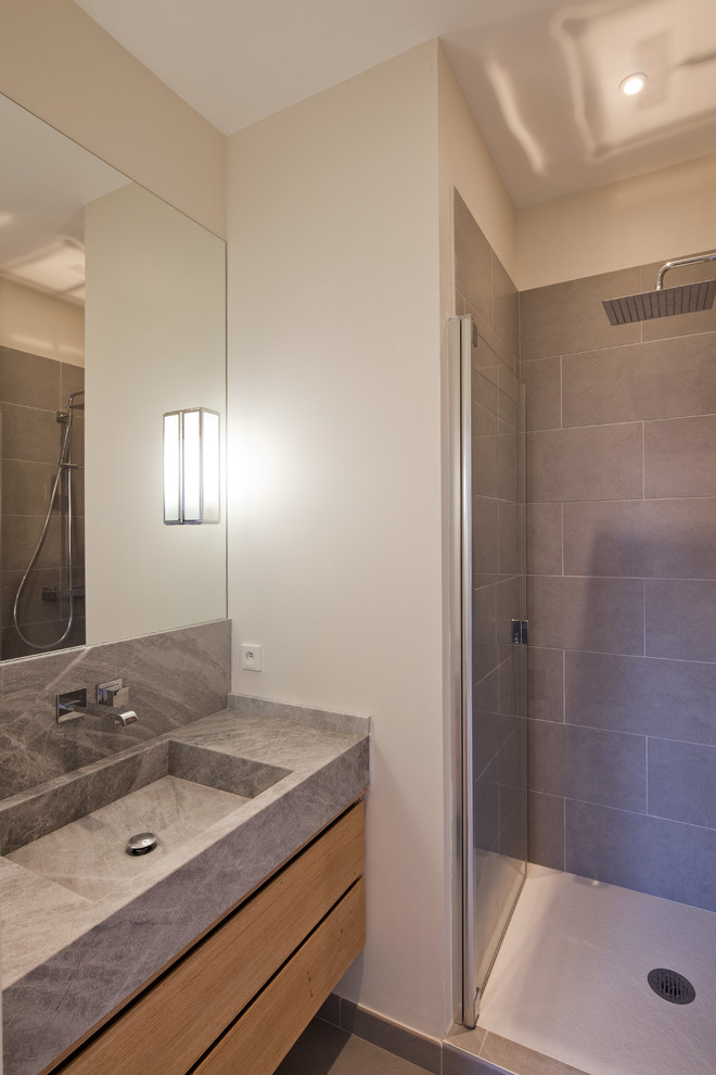 Réalisation d'une petite salle de bain design en bois clair avec un plan vasque, un placard à porte affleurante, un plan de toilette en granite, un carrelage gris, des carreaux de céramique, un mur beige et un sol en carrelage de céramique.