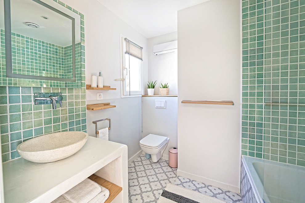 Réalisation d'une petite salle de bain méditerranéenne avec un placard sans porte, une baignoire en alcôve, WC suspendus, un carrelage vert, des carreaux en terre cuite, un mur vert, tomettes au sol, une vasque et un plan de toilette en béton.