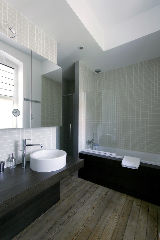 Large contemporary ensuite bathroom in Bordeaux with dark wood cabinets, a built-in bath, a shower/bath combination, beige tiles, ceramic tiles, medium hardwood flooring, a vessel sink, wooden worktops and black worktops.