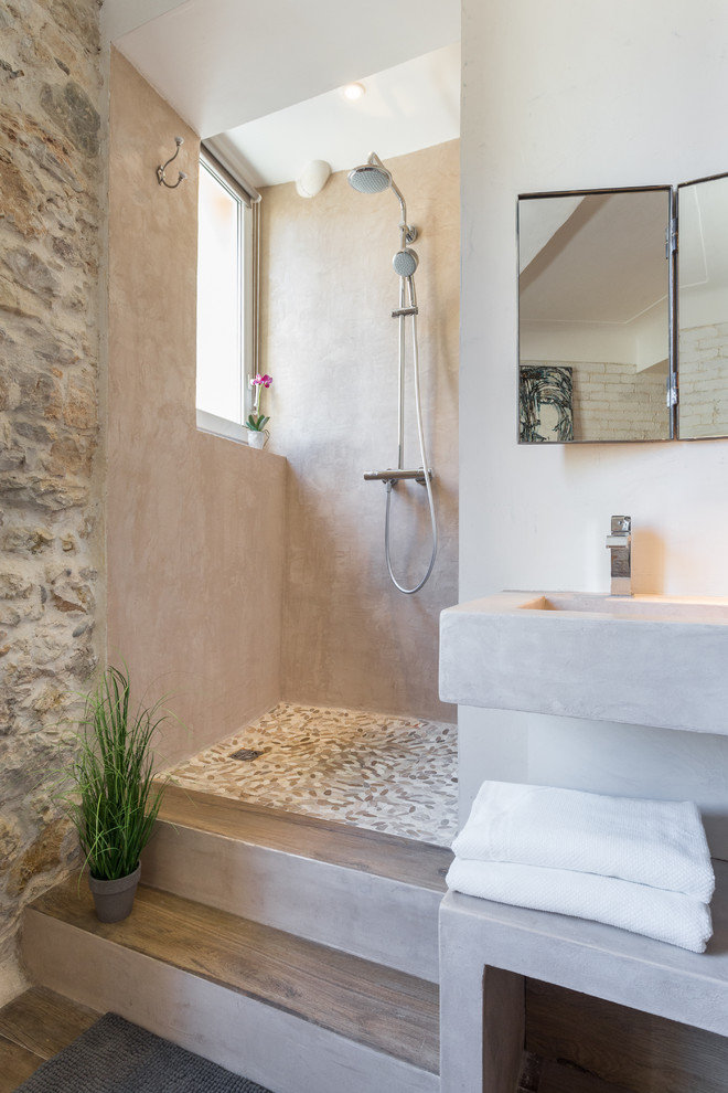 Inspiration pour une petite salle d'eau méditerranéenne avec un lavabo suspendu, une douche ouverte, un placard sans porte, un mur beige, un sol en bois brun, un plan de toilette en béton, aucune cabine, une fenêtre et un mur en pierre.