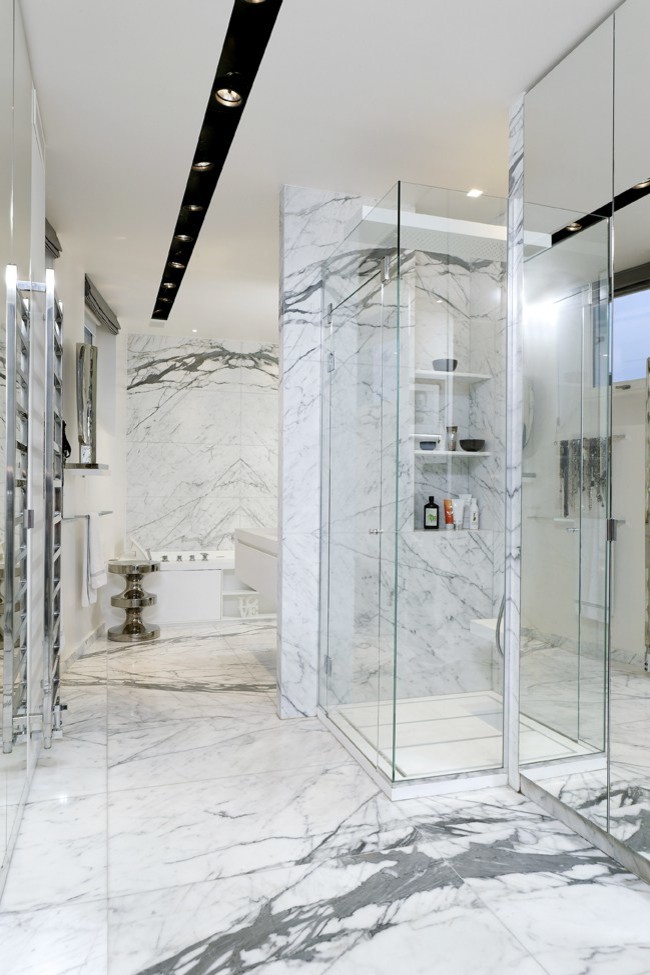 Cette image montre une grande salle d'eau minimaliste avec une douche d'angle, un carrelage de pierre, un carrelage blanc, un carrelage gris et un mur blanc.