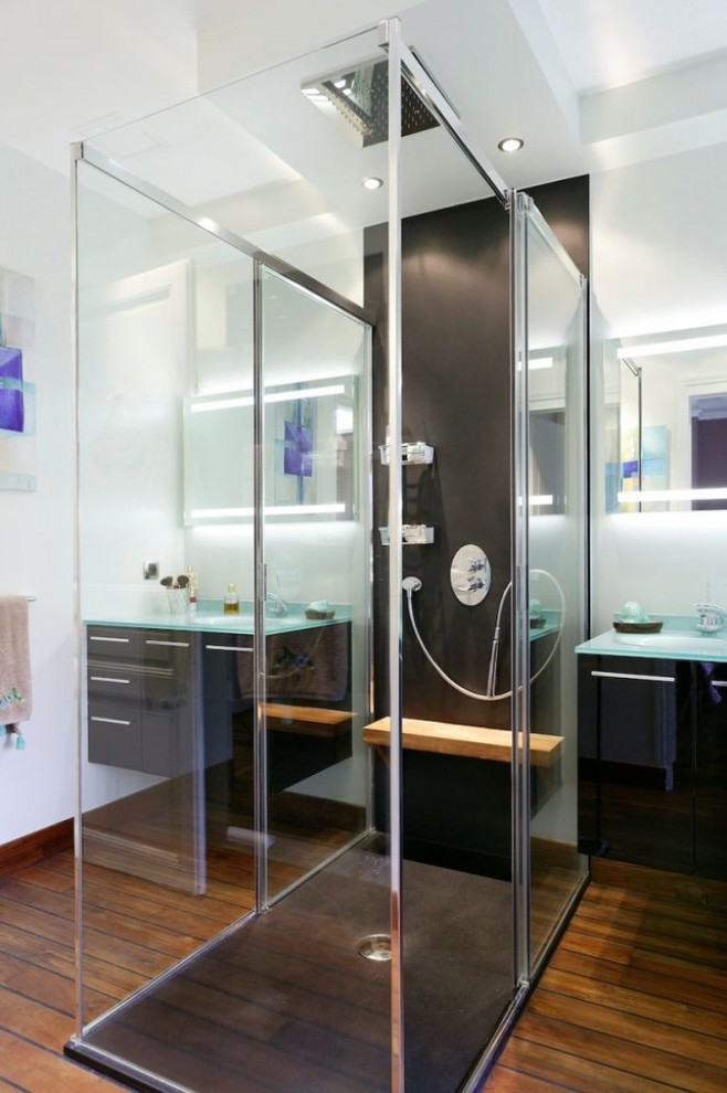 Inspiration för mellanstora moderna badrum med dusch, med svarta skåp, vita väggar, mellanmörkt trägolv, ett integrerad handfat, bänkskiva i glas och en dusch i en alkov