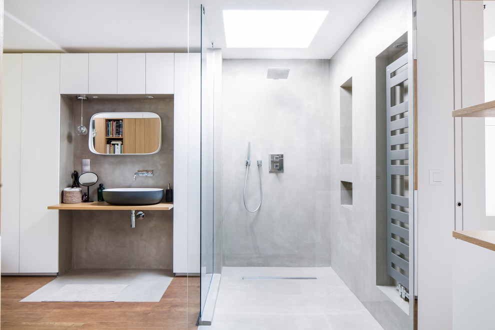 Inredning av ett industriellt beige beige badrum, med släta luckor, vita skåp, en kantlös dusch, vita väggar, ett fristående handfat och brunt golv