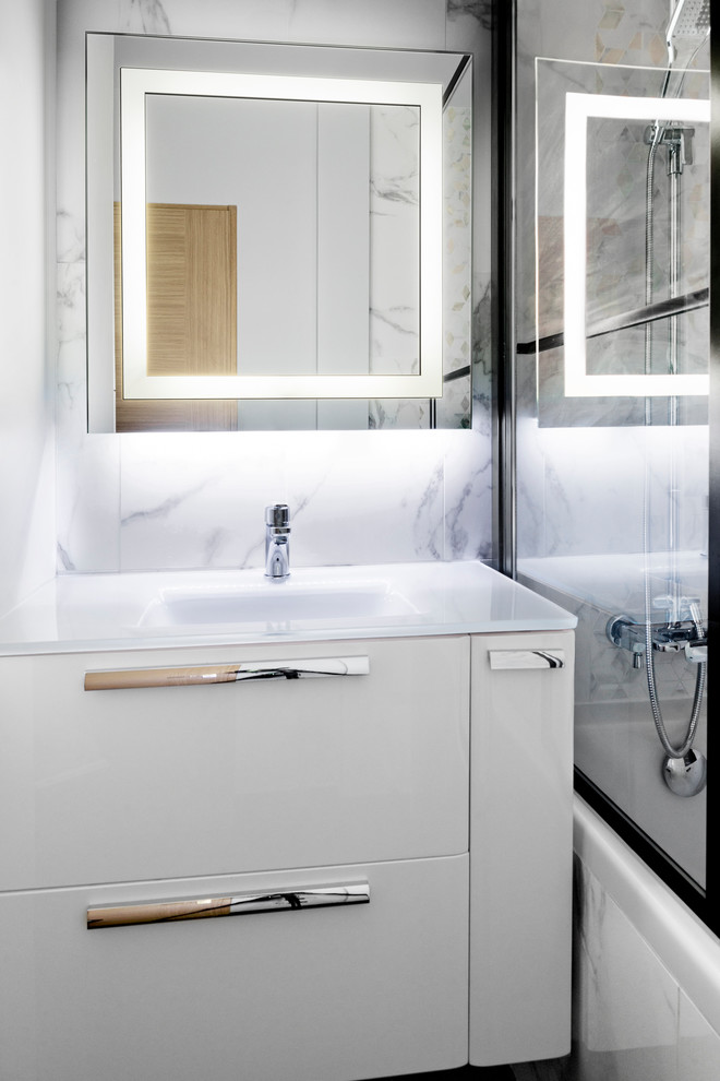 Inredning av ett modernt litet vit vitt en-suite badrum, med luckor med profilerade fronter, vita skåp, ett undermonterat badkar, svart och vit kakel, ett undermonterad handfat och bänkskiva i glas