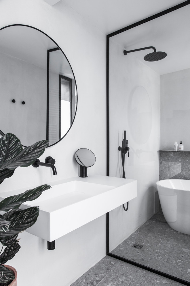 Idéer för ett modernt badrum, med ett fristående badkar, vita väggar, ett väggmonterat handfat och grått golv