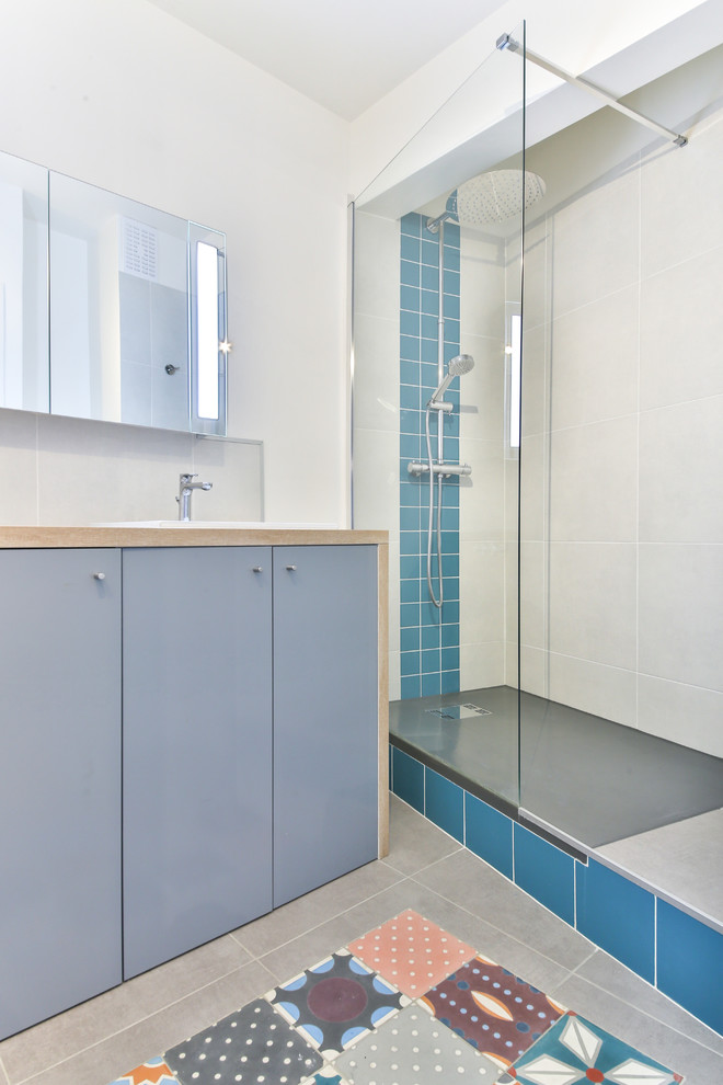 Idée de décoration pour une salle d'eau design de taille moyenne avec des portes de placard grises, un carrelage blanc, un carrelage bleu, un mur blanc, un sol en carrelage de céramique, un plan de toilette en bois, une douche à l'italienne, des carreaux de béton et un lavabo encastré.