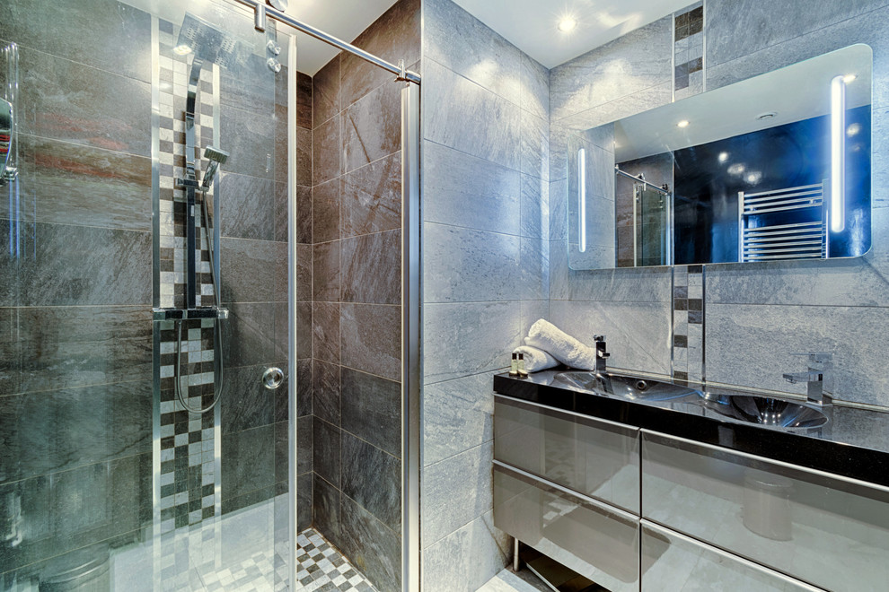 На фото: ванная комната среднего размера в современном стиле с плоскими фасадами, серыми фасадами, душем без бортиков, серой плиткой, керамической плиткой, серыми стенами, полом из керамической плитки, душевой кабиной, раковиной с несколькими смесителями, столешницей из искусственного кварца, серым полом и душем с раздвижными дверями