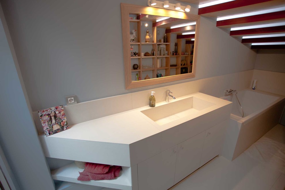 Idée de décoration pour une salle de bain principale design de taille moyenne avec une baignoire encastrée, un mur gris, carreaux de ciment au sol, un lavabo intégré et un sol beige.