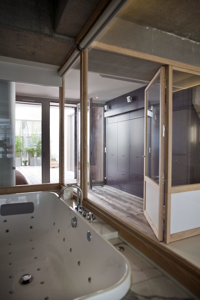 Пример оригинального дизайна: ванная комната в белых тонах с отделкой деревом в современном стиле с гидромассажной ванной, серыми стенами и окном