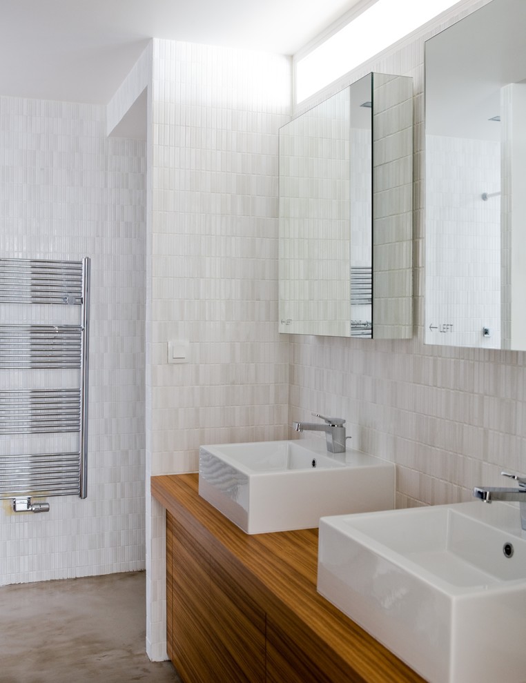 Aménagement d'une salle de bain principale contemporaine en bois brun de taille moyenne avec un placard à porte affleurante, une douche à l'italienne, WC suspendus, un carrelage blanc, des carreaux de céramique, un mur blanc, sol en béton ciré, un lavabo posé et un plan de toilette en bois.