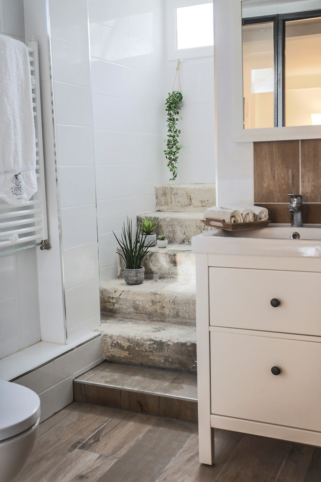 Réalisation d'une salle de bain tradition avec un placard à porte plane, des portes de placard blanches, un carrelage marron, un carrelage blanc, un lavabo intégré, un sol marron et un plan de toilette blanc.