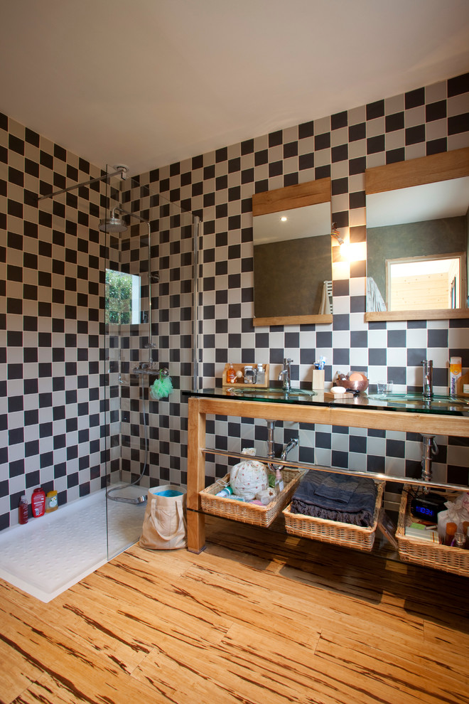Réalisation d'une salle d'eau design en bois clair de taille moyenne avec un placard sans porte, un plan de toilette en verre, une douche d'angle, un mur multicolore, un sol en bois brun, un carrelage noir et blanc et un lavabo intégré.