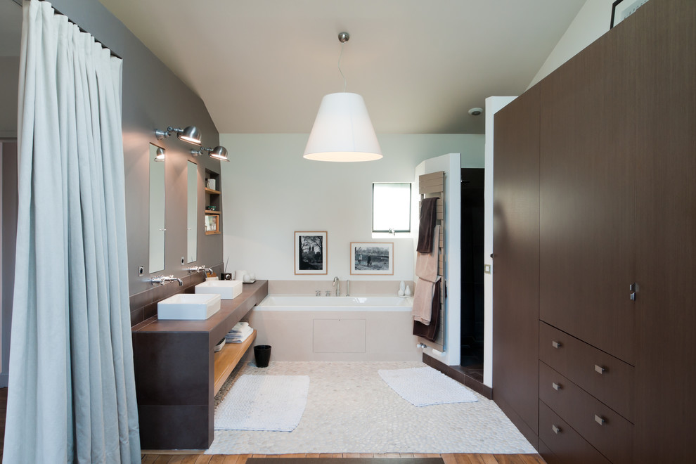 Bathroom - contemporary master pebble tile floor bathroom idea in Paris with a vessel sink, flat-panel cabinets, dark wood cabinets and white walls
