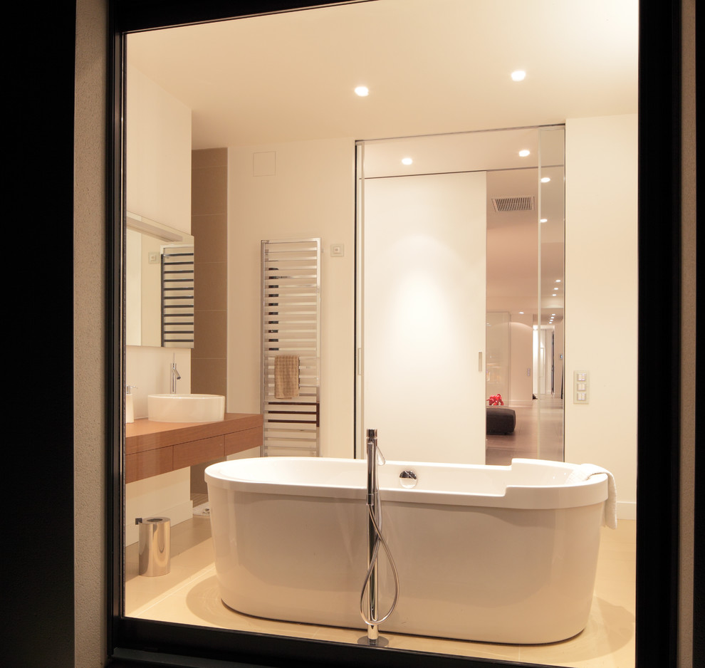 На фото: большая главная ванная комната в стиле модернизм с накладной ванной, белыми стенами, накладной раковиной и столешницей из дерева