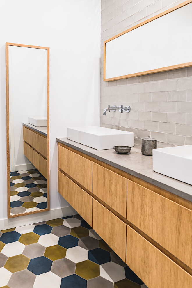 Réalisation d'une salle de bain design en bois brun avec un placard à porte plane, un carrelage gris, un carrelage métro, un mur blanc, une vasque, un plan de toilette en béton, un sol multicolore et un plan de toilette gris.