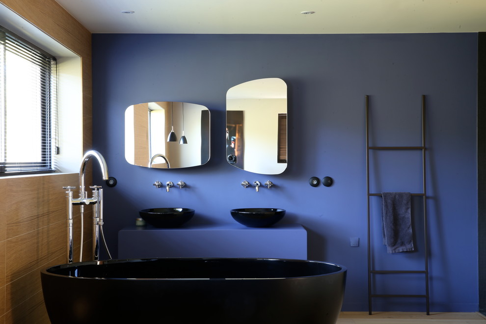 Идея дизайна: главная ванная комната среднего размера в современном стиле с отдельно стоящей ванной, синими стенами, настольной раковиной, столешницей из бетона и синей столешницей