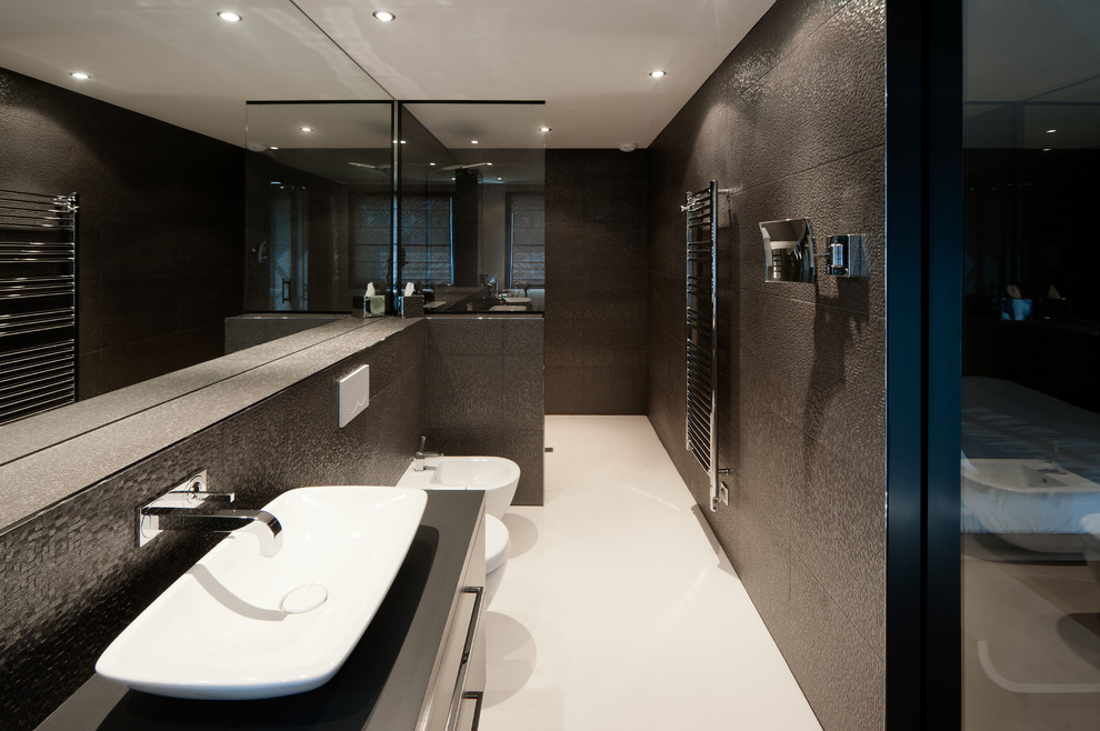 Exemple d'une grande salle de bain principale tendance avec un placard à porte plane, des portes de placard noires, une douche à l'italienne, WC suspendus, un carrelage noir, un mur noir, une vasque, un plan de toilette en carrelage et aucune cabine.