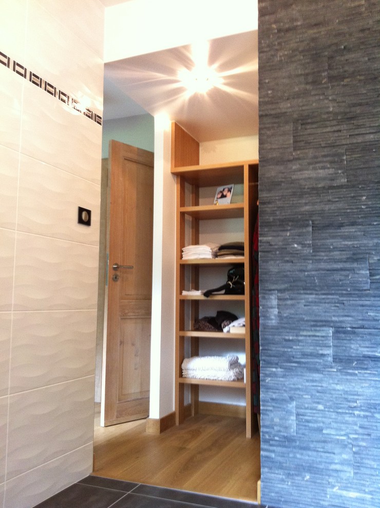Foto på ett mellanstort funkis badrum med dusch, med luckor med upphöjd panel, svarta skåp, en kantlös dusch, svart och vit kakel, grå väggar, klinkergolv i keramik, ett nedsänkt handfat och träbänkskiva