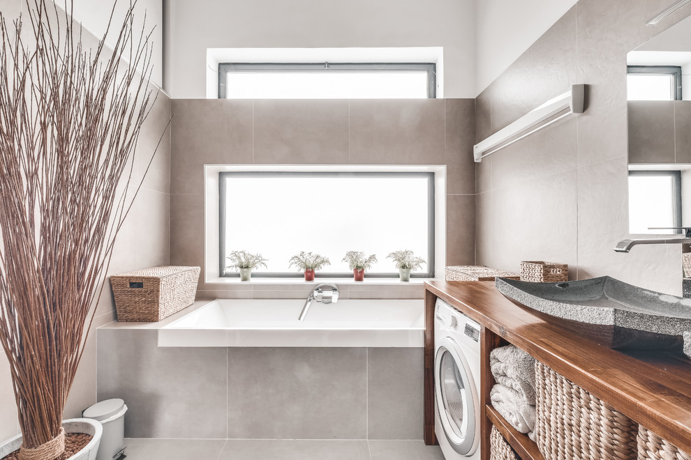 Idéer för ett litet modernt brun en-suite badrum, med öppna hyllor, en kantlös dusch, grå kakel, porslinskakel, klinkergolv i porslin, ett nedsänkt handfat, träbänkskiva, grått golv, ett undermonterat badkar och grå väggar