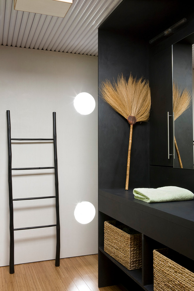 Imagen de cuarto de baño principal actual de tamaño medio con armarios abiertos, paredes negras y suelo de madera en tonos medios