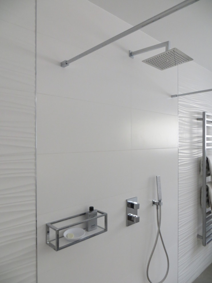 На фото: большая главная ванная комната в стиле модернизм с фасадами с выступающей филенкой, белыми фасадами, накладной ванной, душем без бортиков, инсталляцией, белой плиткой, керамической плиткой, белыми стенами, полом из керамической плитки, консольной раковиной, столешницей из искусственного камня, серым полом, открытым душем и белой столешницей с