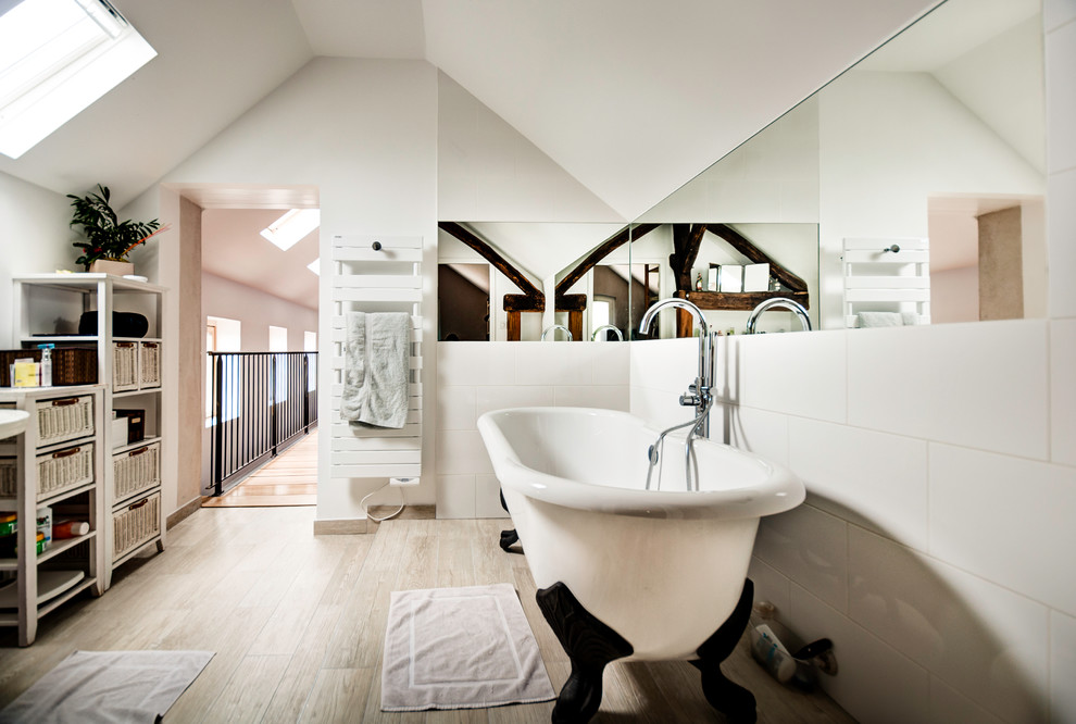 Foto de cuarto de baño principal actual grande con bañera con patas, baldosas y/o azulejos blancos, paredes blancas y suelo de madera clara