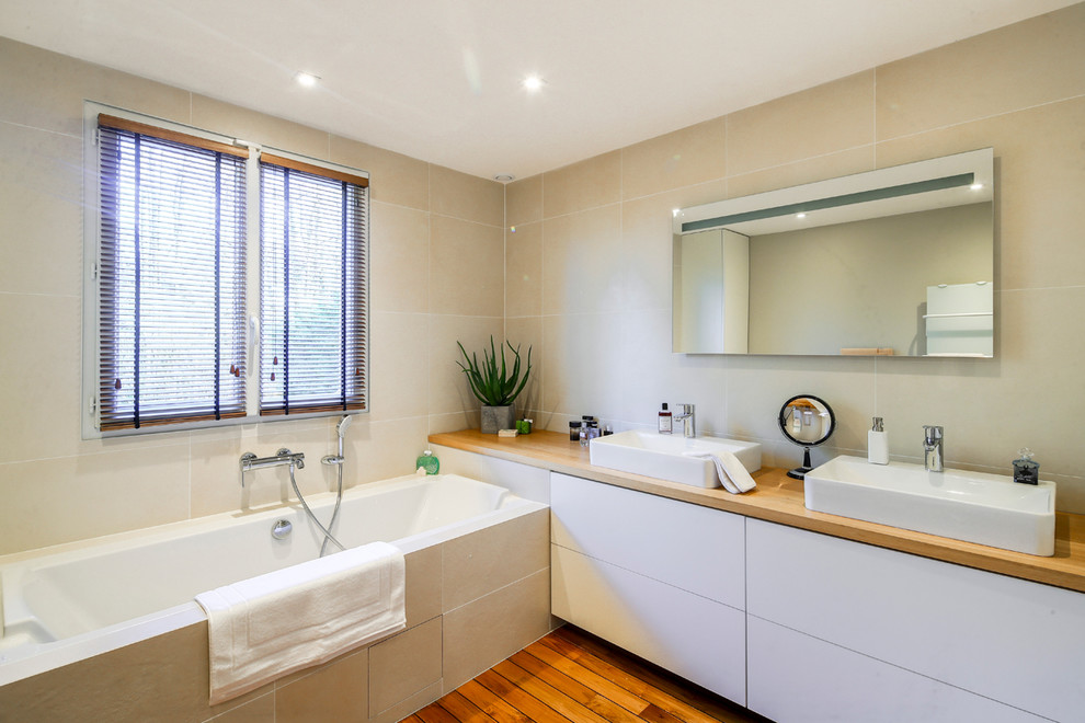 Large rural ensuite bathroom in Paris with beaded cabinets, a freestanding bath, a built-in shower, beige walls, light hardwood flooring and wooden worktops.