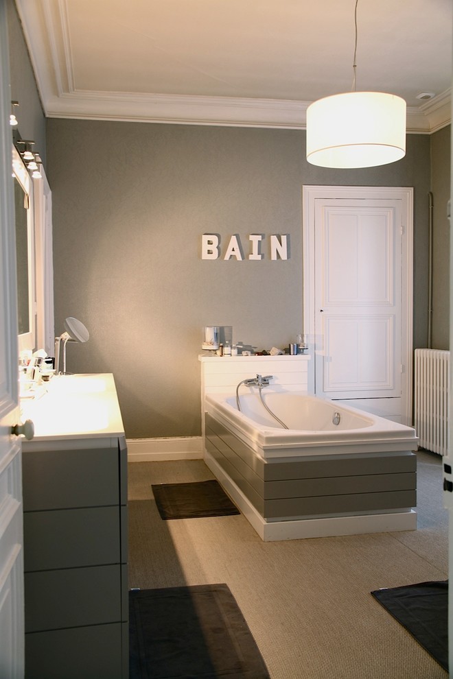 Idée de décoration pour une grande salle de bain principale design avec des portes de placard grises, une baignoire posée et un mur gris.