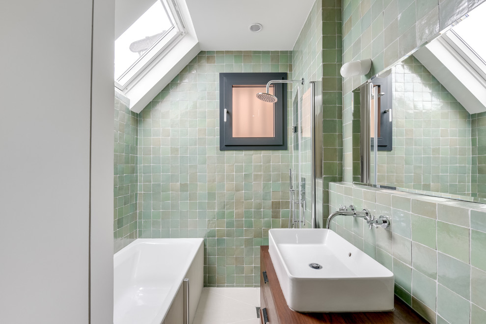 На фото: ванная комната в стиле неоклассика (современная классика) с плоскими фасадами, темными деревянными фасадами, ванной в нише, душевой комнатой, зеленой плиткой, настольной раковиной, столешницей из дерева, открытым душем и коричневой столешницей с