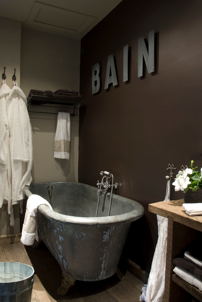 Industriell inredning av ett mellanstort en-suite badrum, med ett badkar med tassar, bruna väggar, öppna hyllor och mellanmörkt trägolv