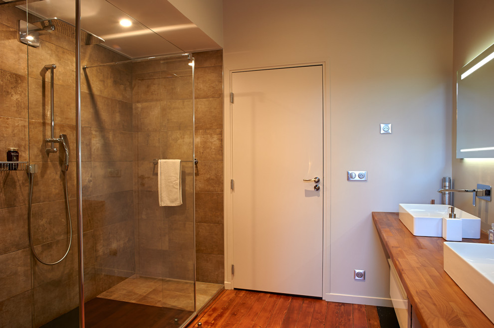 Пример оригинального дизайна: большая ванная комната в современном стиле с плиткой из листового камня, серыми стенами, деревянным полом, накладной раковиной, столешницей из дерева, открытым душем и коричневой столешницей