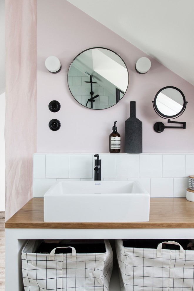 Kleines Skandinavisches Badezimmer mit offenen Schränken, weißen Schränken, weißen Fliesen, Keramikfliesen, rosa Wandfarbe, Aufsatzwaschbecken, Waschtisch aus Holz und beiger Waschtischplatte in Paris