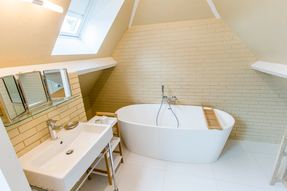 Пример оригинального дизайна: большая главная ванная комната в белых тонах с отделкой деревом в современном стиле с светлыми деревянными фасадами, накладной ванной, бежевой плиткой, бежевыми стенами, полом из керамической плитки, белым полом, тумбой под одну раковину и кирпичными стенами