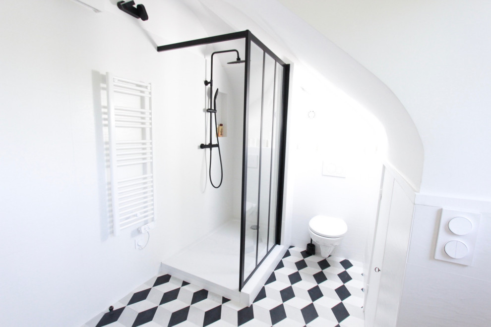 Réalisation d'une salle d'eau avec une douche ouverte, WC suspendus, un carrelage blanc, carreaux de ciment au sol et un sol noir.